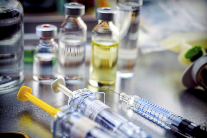 Vials of different size next to syringes at a hospital table, conceptual image